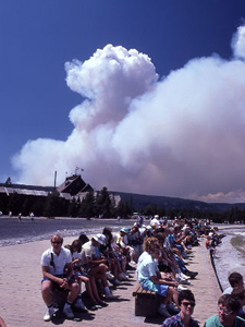 写真16：オールドウェイスフルで間欠泉の噴出を待つ人たちの背後に立ち上る森林火災の煙（1988年 NPS PHOTO）